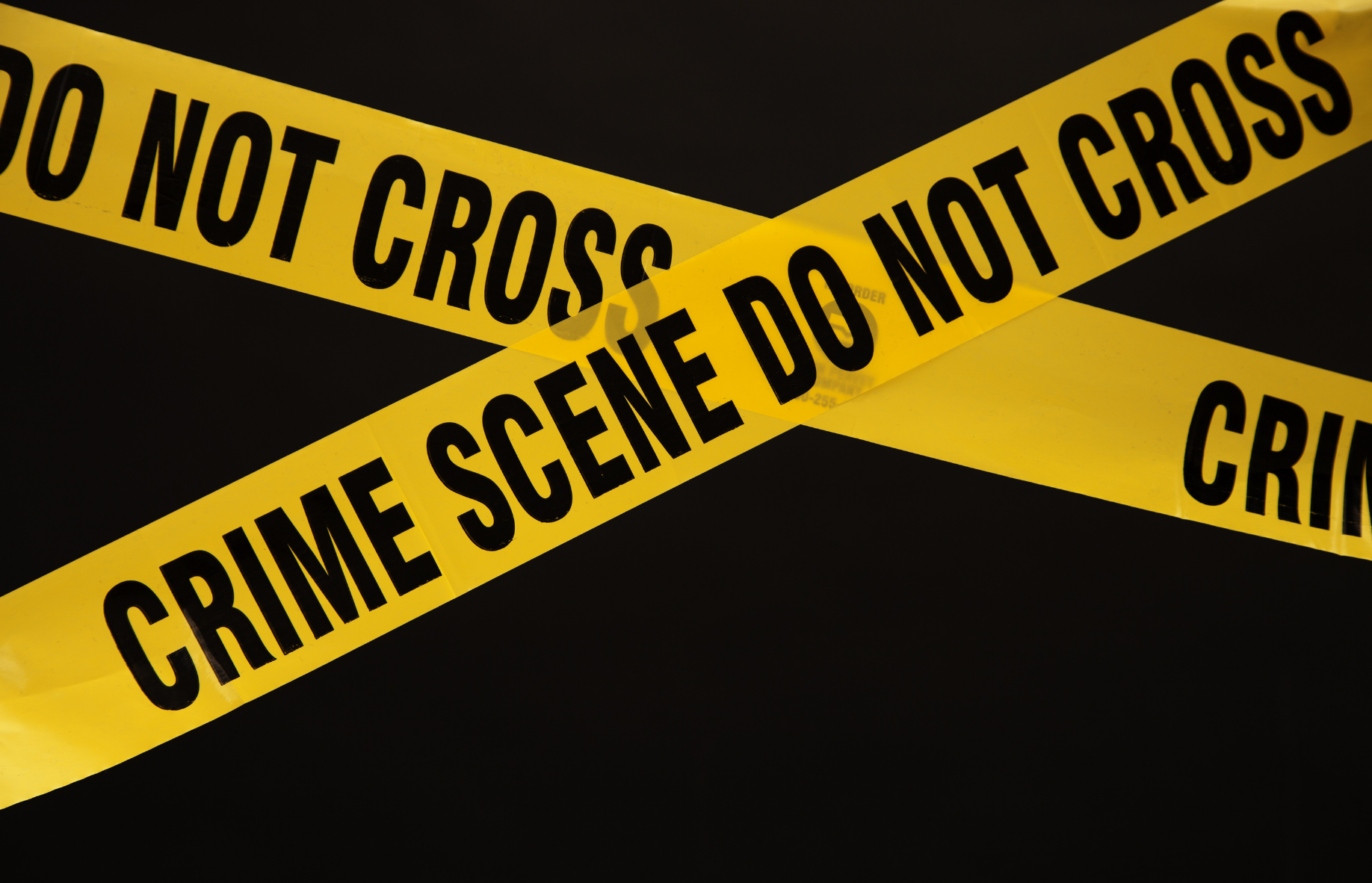 Yellow crime scene tape over a dark background